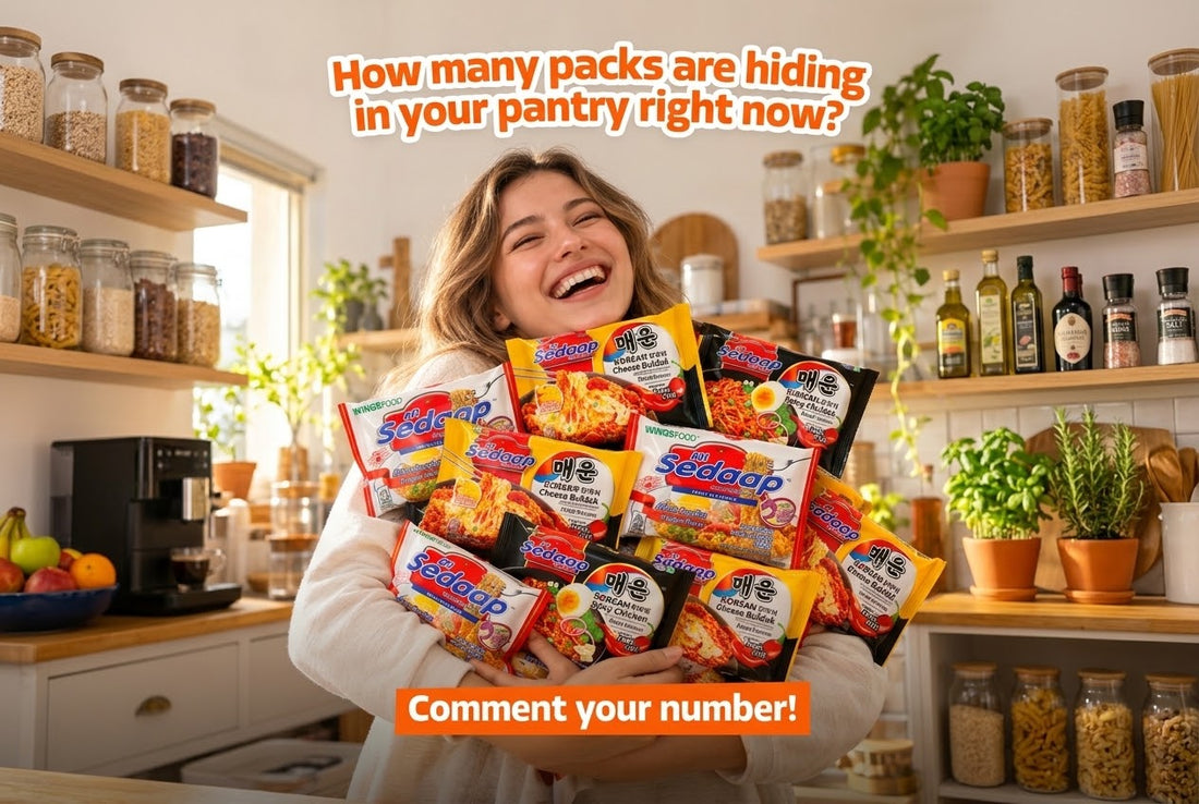 A smiling young woman standing in a bright kitchen, holding a large armful of assorted Mi Sedaap instant noodle packets.