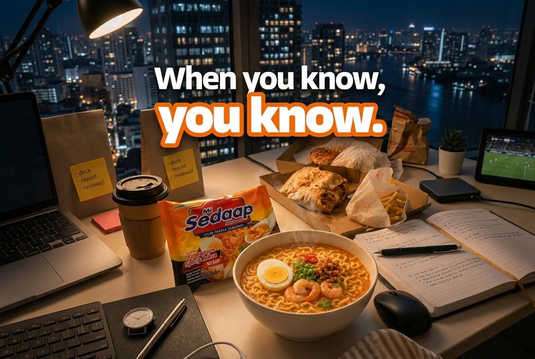 Late night desk scene with a bowl of Mi Sedaap Singaporean Spicy Laksa noodles, shrimp, and egg, alongside a laptop and takeout food.