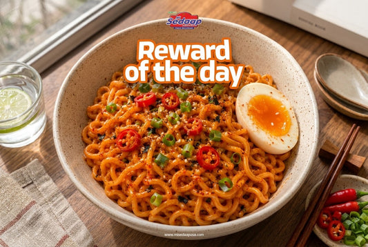 Bowl of glossy red-sauced Mi Sedaap Korean Spicy Chicken noodles topped with sliced chili, scallions, sesame seeds, and a soft-boiled egg.