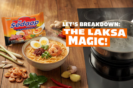 Bowl of Mi Sedaap Singapore Spicy Laksa with shrimp, egg, and sambal beside fresh laksa ingredients and a boiling pot.