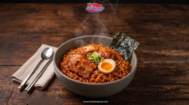 Mi Sedaap Korean instant noodles with spicy chicken and cheese buldak flavors served in bowls with chopsticks, garnished with egg, cheese, and Korean-inspired toppings.